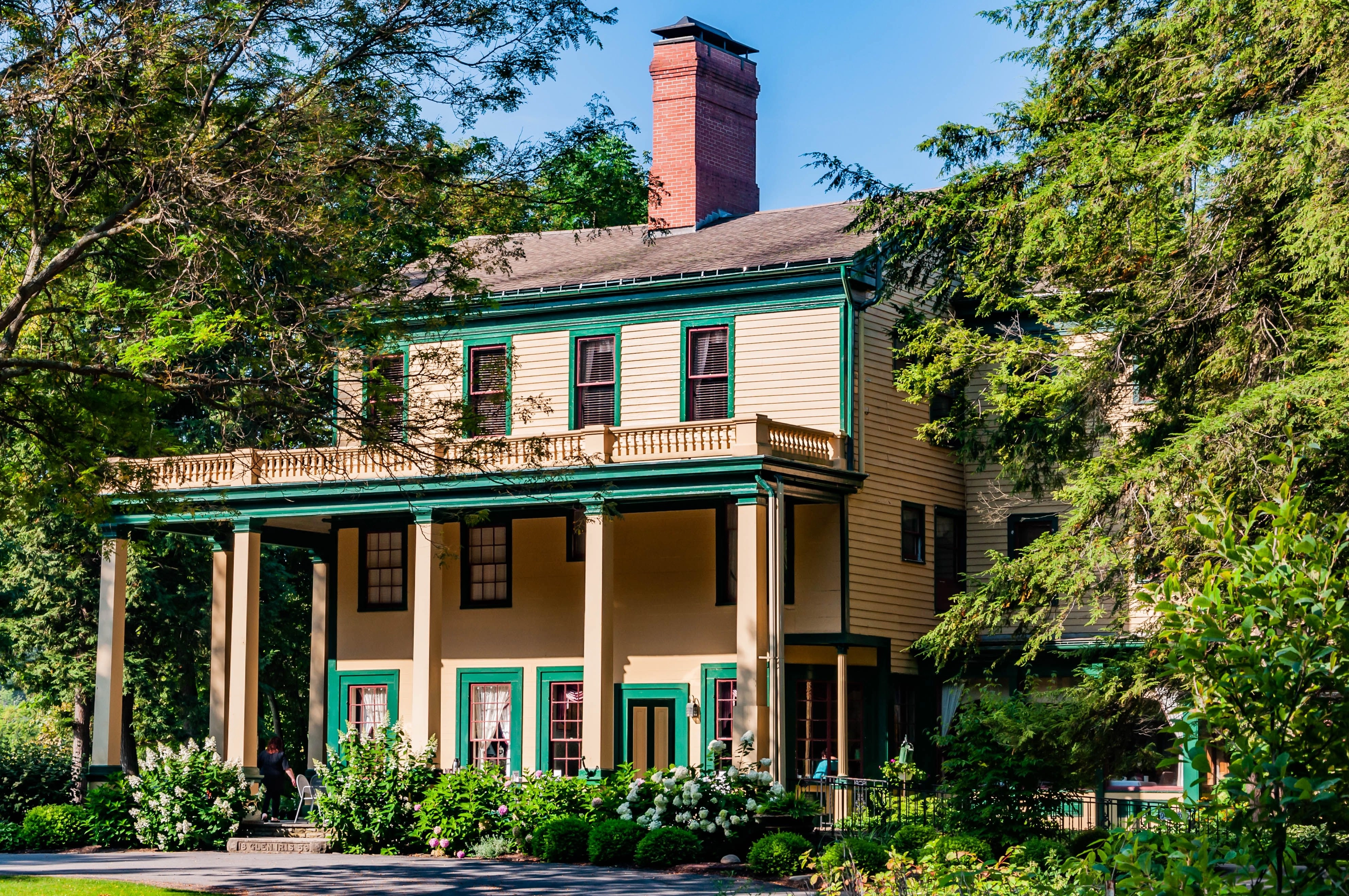 Historic two-story inn in Glen Iris surrounded by lush greenery and equipped with a porch