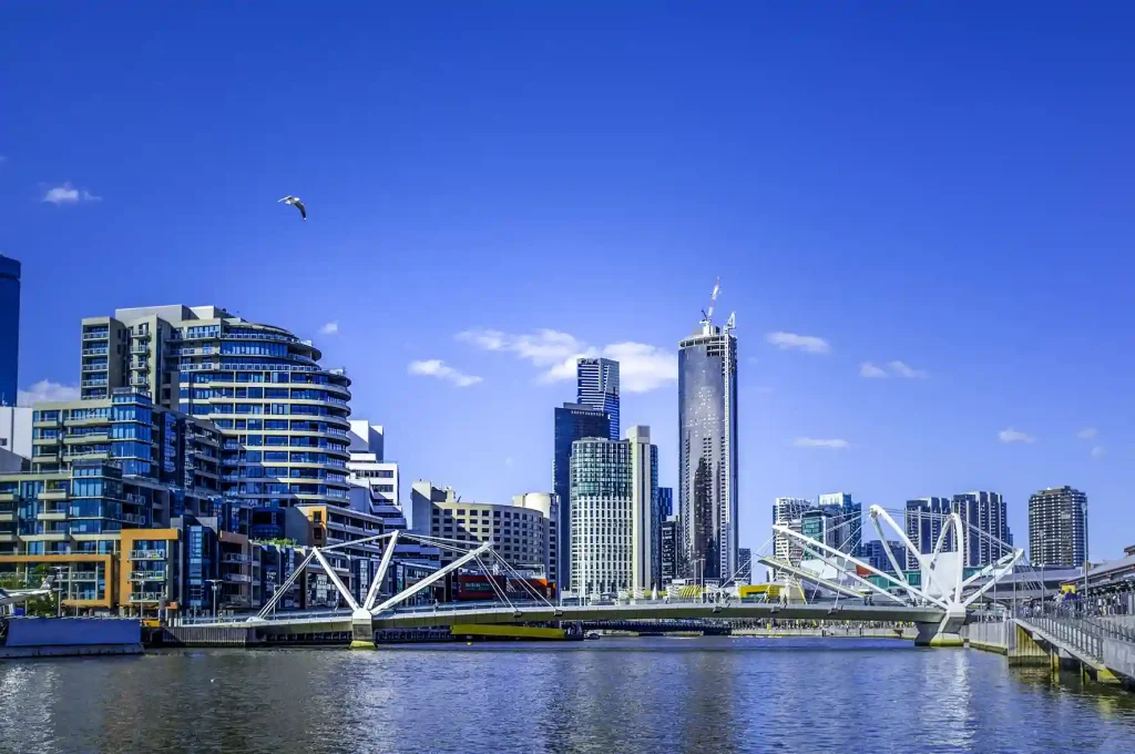Seafarers Bridge over Yarra River in South Wharf, showcasing the modern architecture and vibrant cityscape of Melbourne CBD under a clear blue sky.