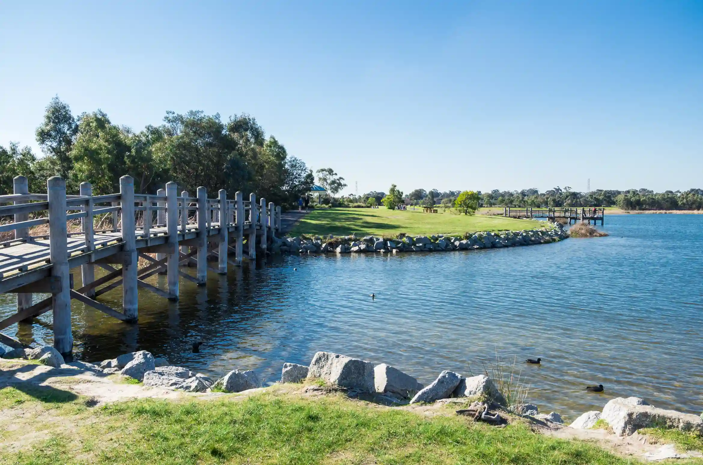 Wooden bridge over a tranquil lake in a Karkarook park in Moorabbin