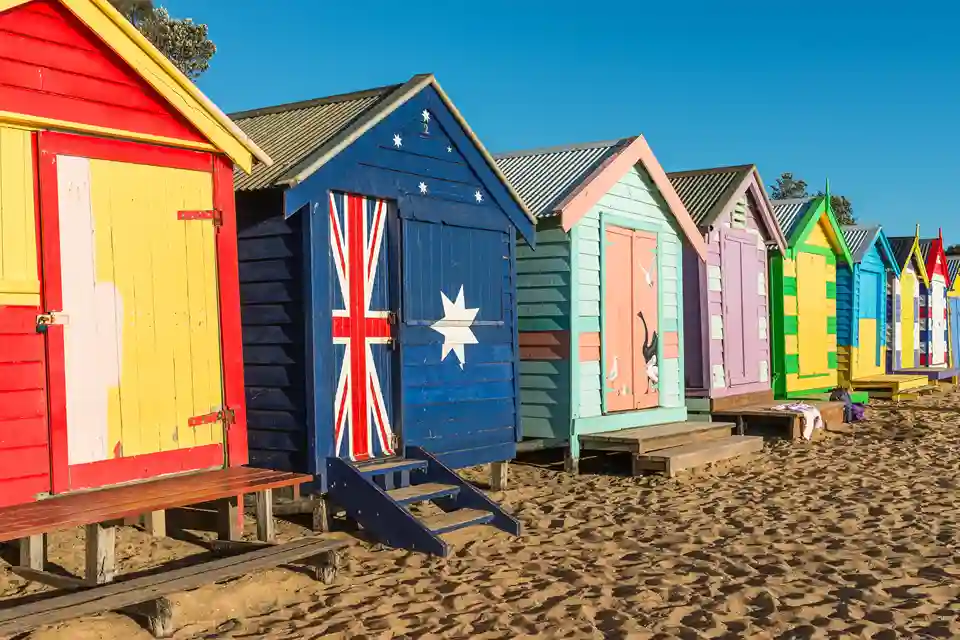 Iconic colourful Brighton Beach bathing boxes on sandy shores under a bright blue sky.