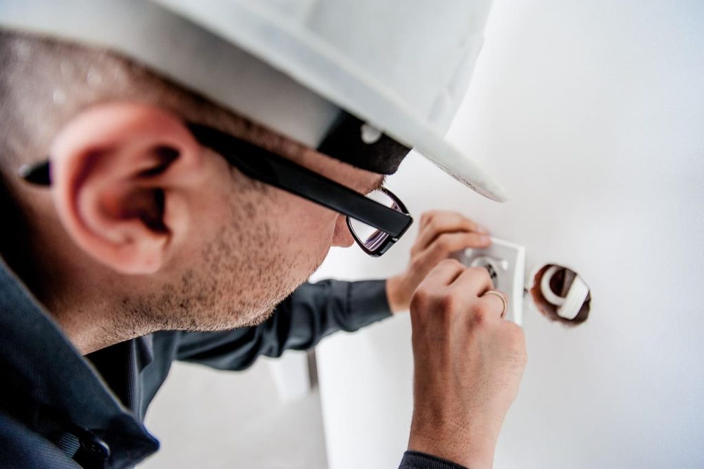 Professional Electrician is working on electrical wiring in a wall