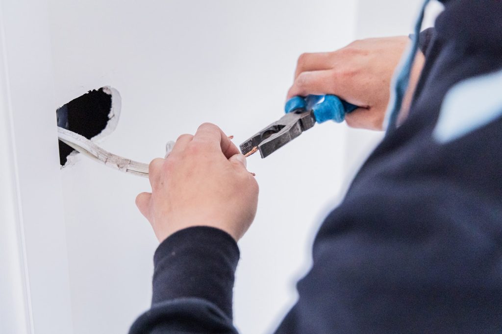 Electrician with pliers preparing cables