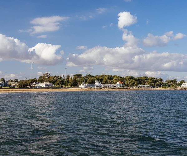Williamstown beach featuring houses along the coastline and tranquil water in the foreground.