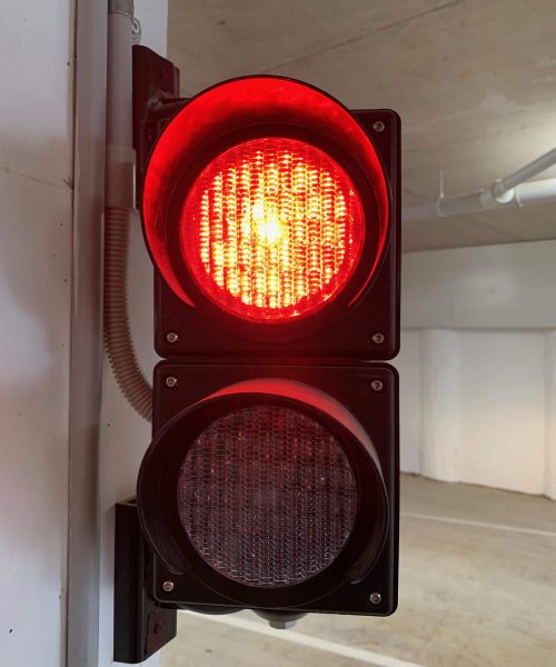 Close-up of a red car park signal light illuminated, indicating stop in a parking garage.